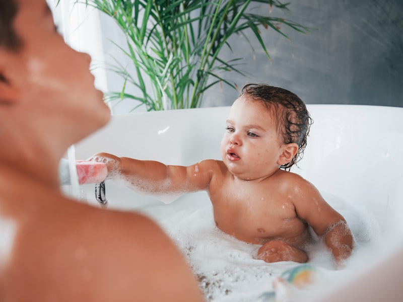 Mutter badet ihr Baby sanft in einer Babywanne