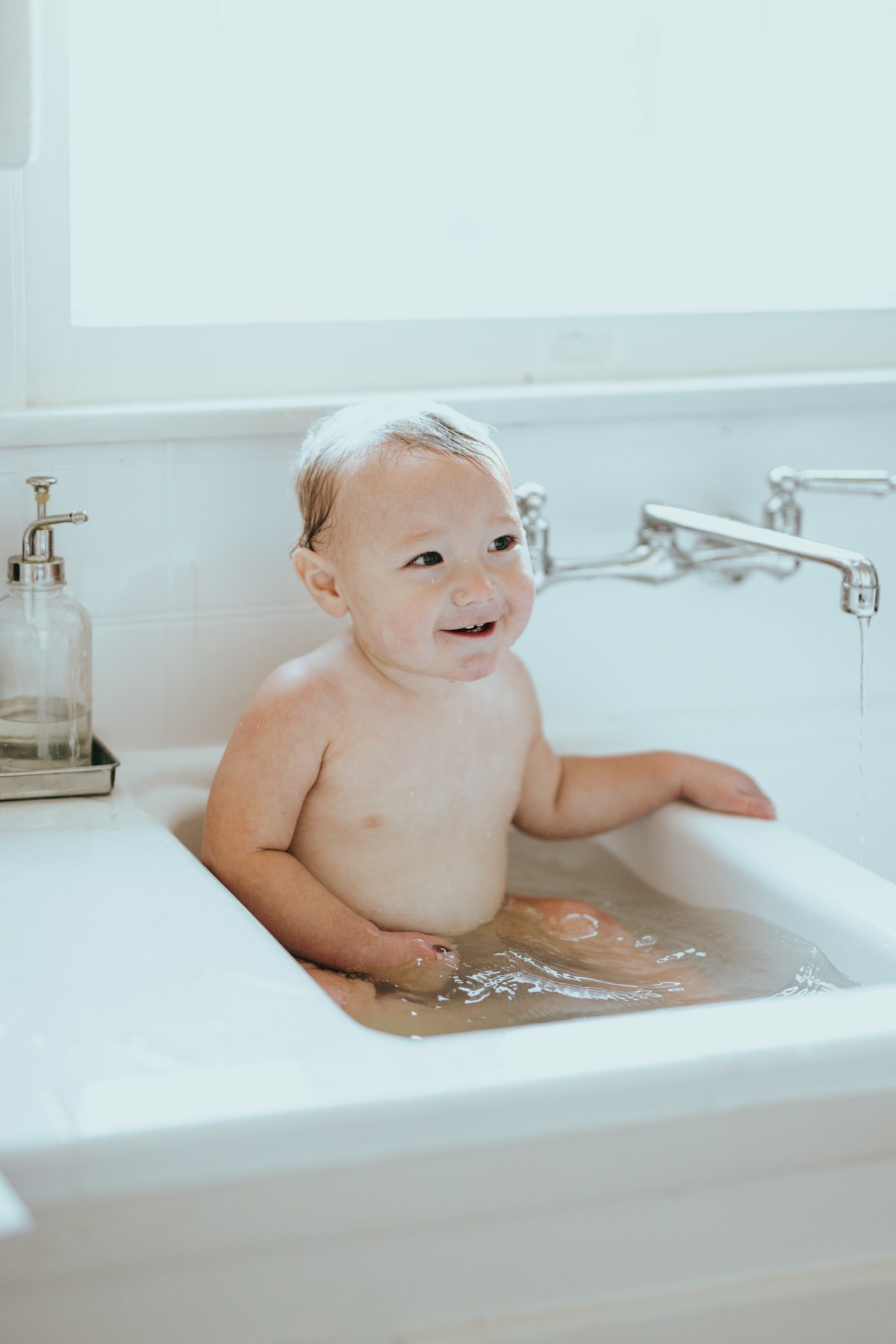 Baby sitzt fröhlich in einem Badesitz in der Badewanne
